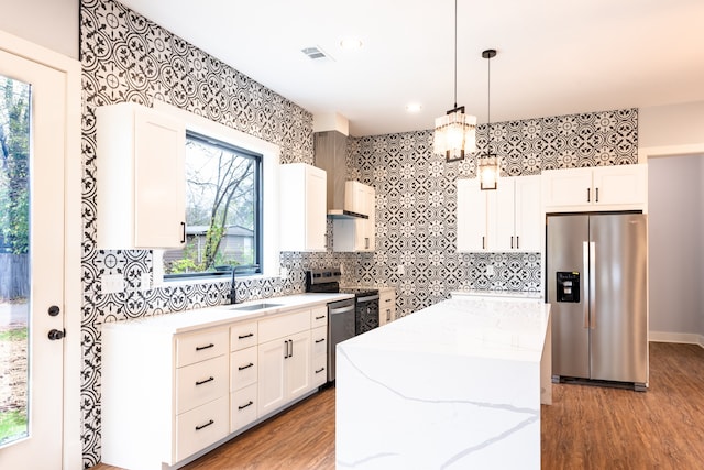 kitchen with decorative light fixtures, a wealth of natural light, white cabinetry, and appliances with stainless steel finishes