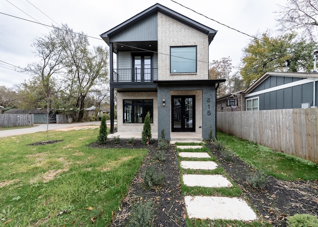 view of front of home with french doors, a balcony, and a front lawn