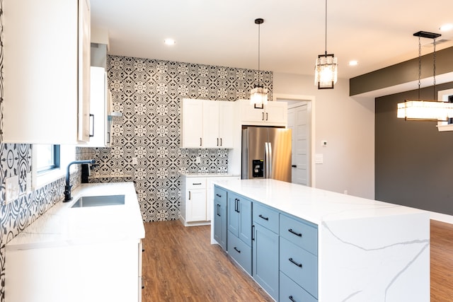 kitchen featuring stainless steel fridge with ice dispenser, white cabinetry, hanging light fixtures, and a kitchen island