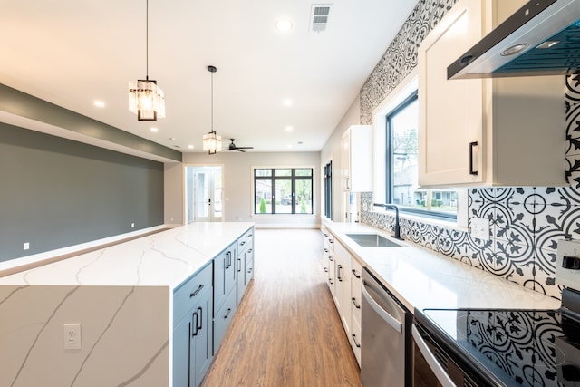 kitchen featuring white cabinets, light stone counters, decorative light fixtures, dishwasher, and range hood