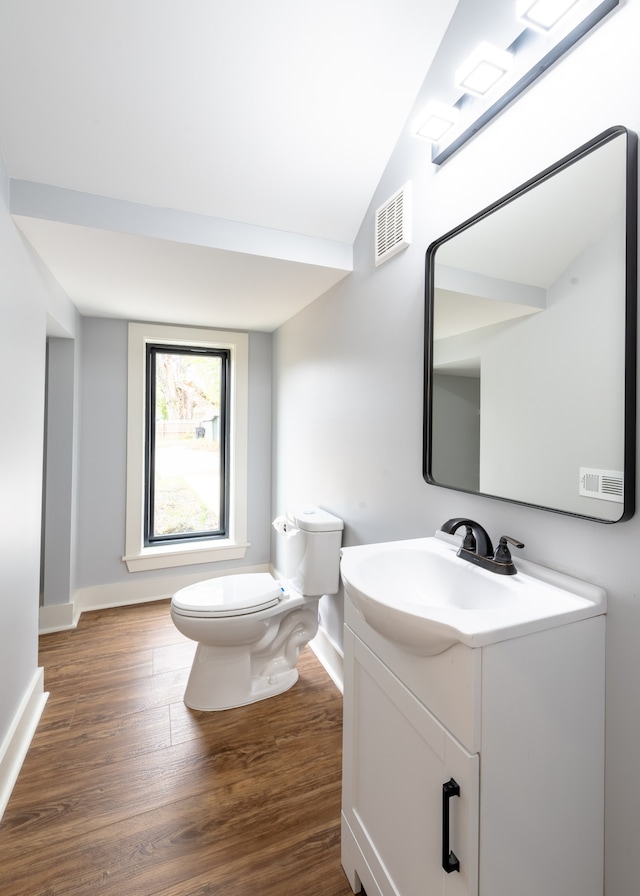 bathroom with toilet, vanity, vaulted ceiling, and hardwood / wood-style flooring