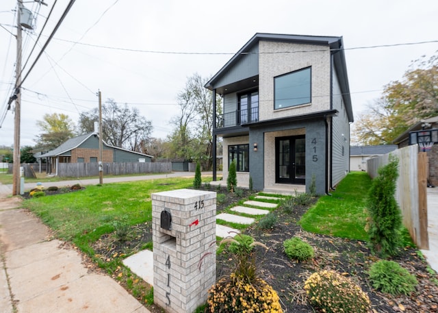 view of front facade with a front lawn, a balcony, and french doors