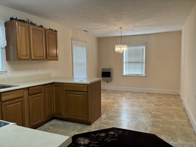 kitchen featuring a notable chandelier, heating unit, kitchen peninsula, pendant lighting, and a textured ceiling