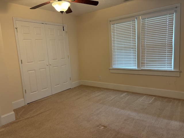 unfurnished bedroom with ceiling fan, light colored carpet, and a closet