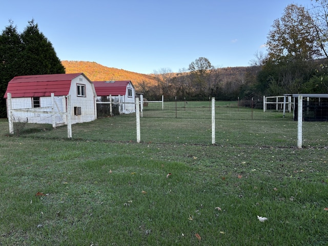 view of yard featuring a mountain view, a rural view, and an outdoor structure