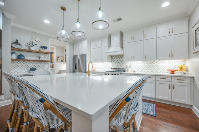 kitchen with dark wood-type flooring, hanging light fixtures, custom range hood, appliances with stainless steel finishes, and white cabinetry