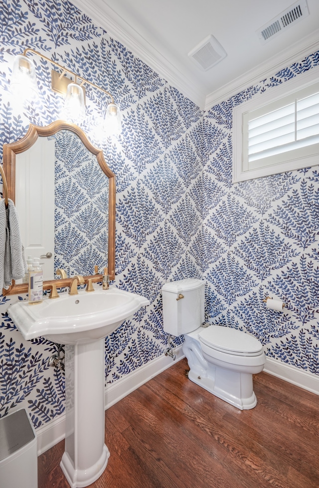 bathroom with wood-type flooring, toilet, and crown molding