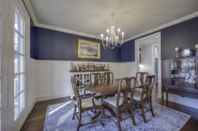 dining area with dark hardwood / wood-style flooring, ornamental molding, and an inviting chandelier