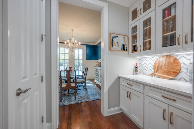 kitchen featuring a notable chandelier, dark hardwood / wood-style flooring, white cabinetry, and crown molding