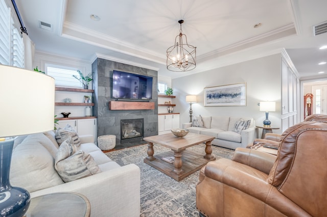 living room featuring crown molding, a tile fireplace, and a tray ceiling