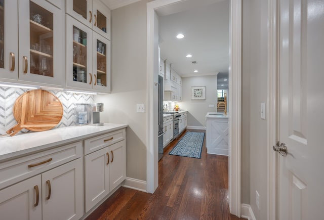 bar featuring dark hardwood / wood-style floors, backsplash, high quality appliances, white cabinets, and ornamental molding