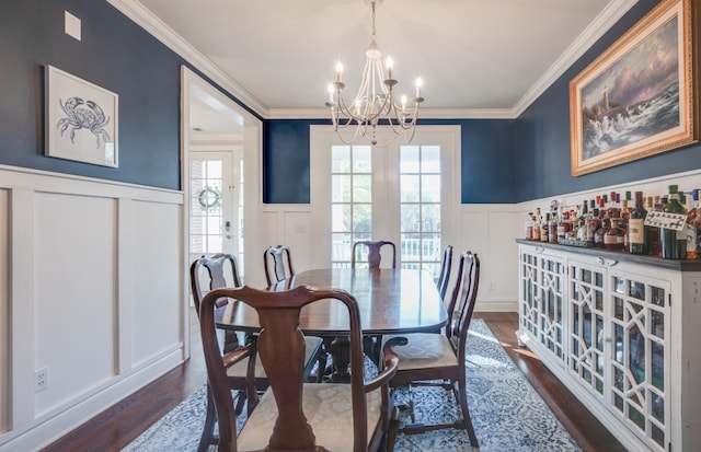 dining space featuring ornamental molding, an inviting chandelier, french doors, and dark wood-type flooring