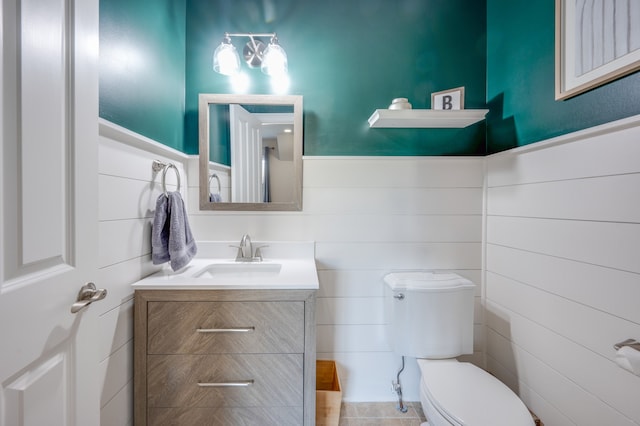 bathroom featuring tile patterned flooring, vanity, tile walls, and toilet