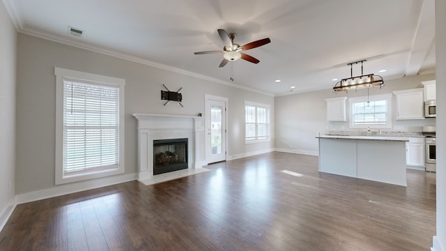 unfurnished living room with wood-type flooring, plenty of natural light, and ornamental molding