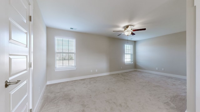 carpeted empty room with ceiling fan and a wealth of natural light