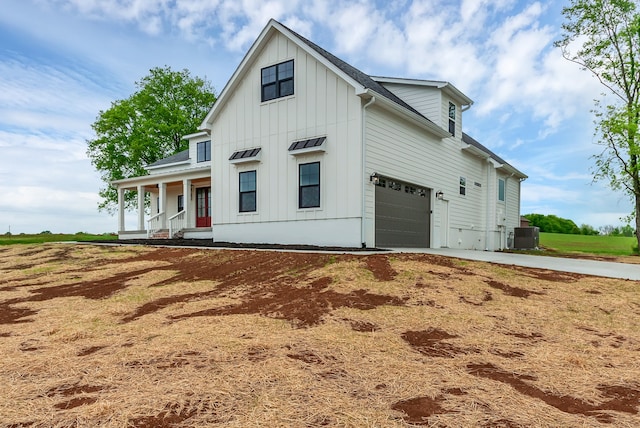 modern inspired farmhouse featuring central air condition unit, covered porch, and a garage