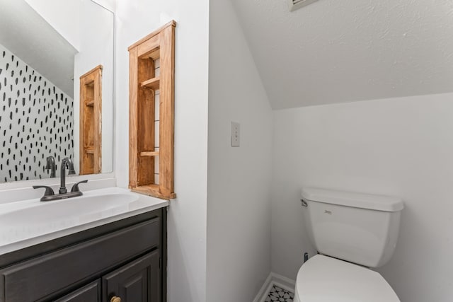 bathroom with vanity, a textured ceiling, toilet, and lofted ceiling