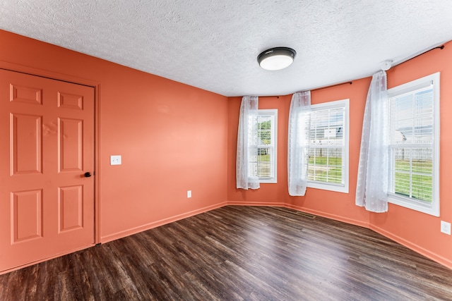 empty room with a textured ceiling and dark wood-type flooring