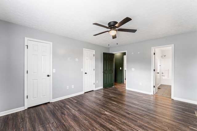 unfurnished bedroom featuring dark hardwood / wood-style floors, ceiling fan, a textured ceiling, and ensuite bath