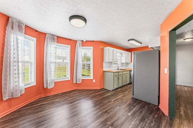 kitchen featuring stainless steel fridge, dark wood-type flooring, green cabinetry, and a healthy amount of sunlight