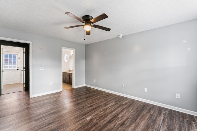 unfurnished bedroom featuring connected bathroom, ceiling fan, sink, dark hardwood / wood-style floors, and a textured ceiling