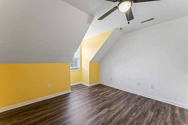 additional living space with ceiling fan, dark hardwood / wood-style flooring, a textured ceiling, and vaulted ceiling