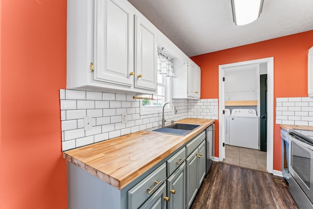 kitchen with sink, separate washer and dryer, dark hardwood / wood-style floors, white cabinetry, and butcher block counters