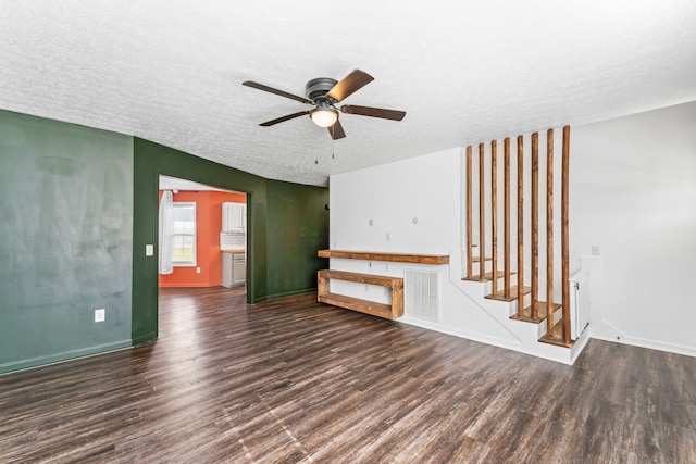 unfurnished living room featuring ceiling fan, dark hardwood / wood-style flooring, and a textured ceiling