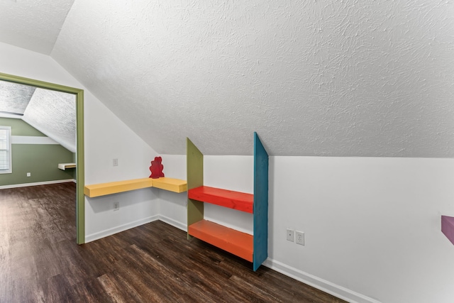 bonus room featuring a textured ceiling, lofted ceiling, and dark wood-type flooring