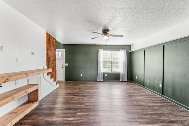 unfurnished living room with ceiling fan, dark wood-type flooring, and a textured ceiling