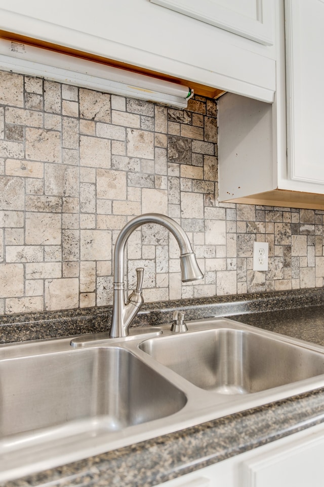 details featuring white cabinets, tasteful backsplash, and sink