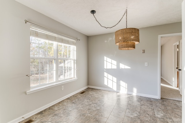 unfurnished dining area with a textured ceiling