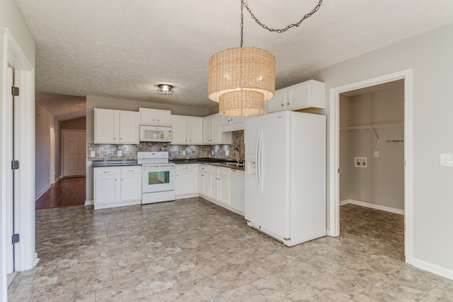 kitchen featuring white appliances, white cabinets, sink, hanging light fixtures, and tasteful backsplash