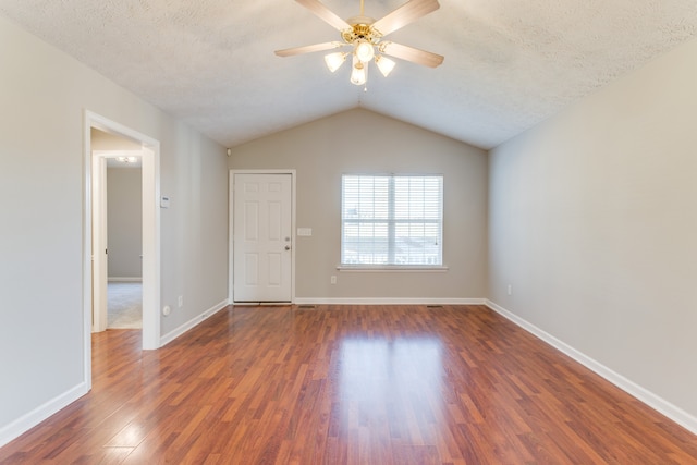 empty room with vaulted ceiling, ceiling fan, dark hardwood / wood-style flooring, and a textured ceiling