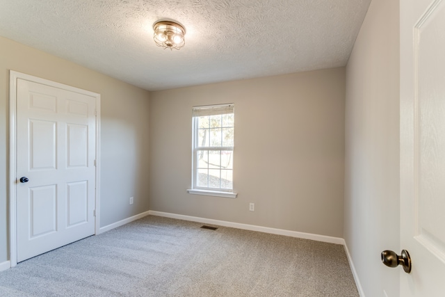 unfurnished room with carpet flooring and a textured ceiling