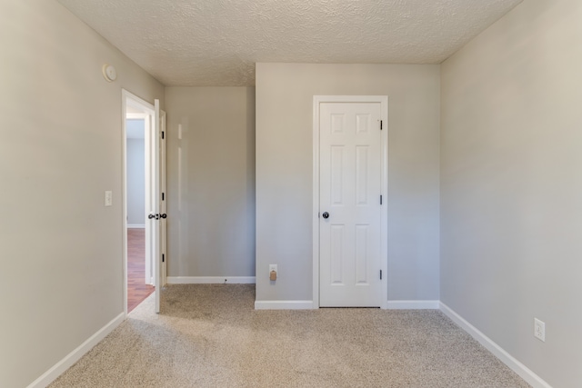 unfurnished bedroom with light carpet and a textured ceiling