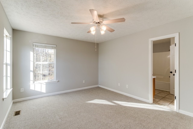 carpeted empty room featuring ceiling fan and a textured ceiling