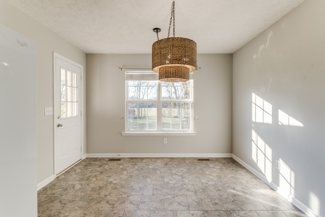 unfurnished dining area with a textured ceiling