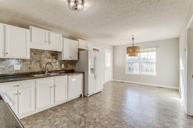 kitchen featuring white appliances, sink, hanging light fixtures, decorative backsplash, and white cabinetry