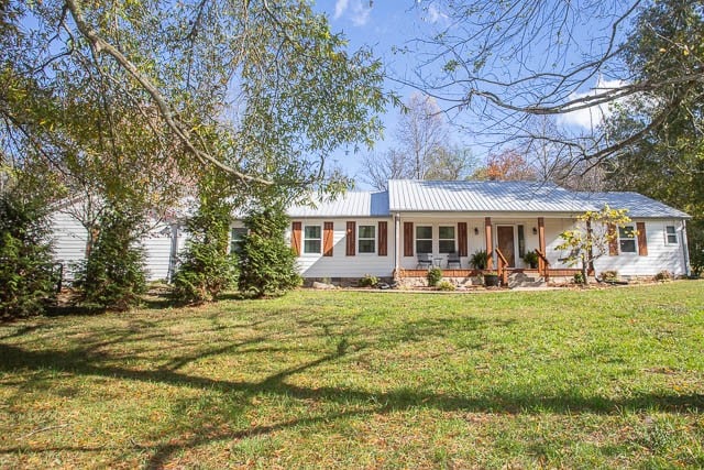 ranch-style house with a porch and a front lawn