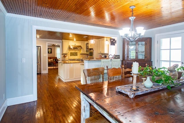 dining space featuring a chandelier, crown molding, wood ceiling, and dark wood-type flooring