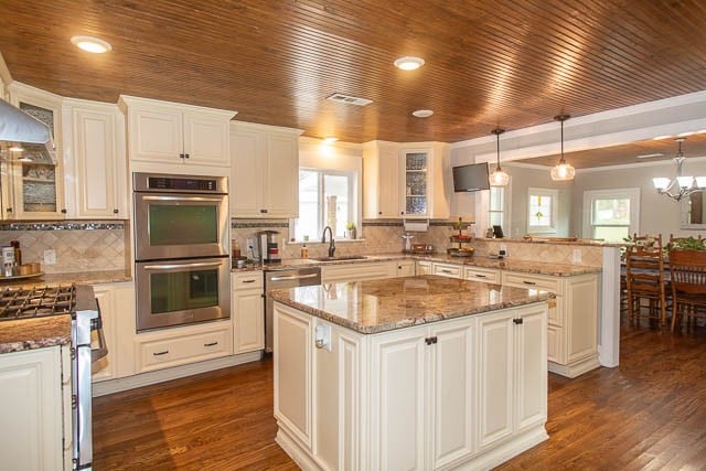 kitchen featuring decorative light fixtures, stainless steel appliances, a kitchen island, and dark wood-type flooring