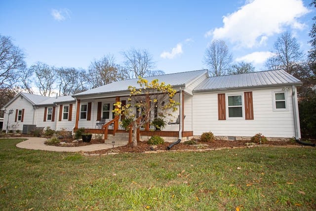 view of front of house featuring a front yard, a porch, and central AC unit