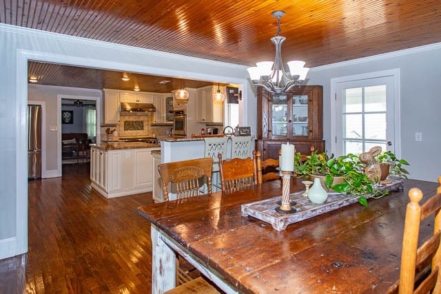 dining area featuring crown molding, dark hardwood / wood-style flooring, and a chandelier