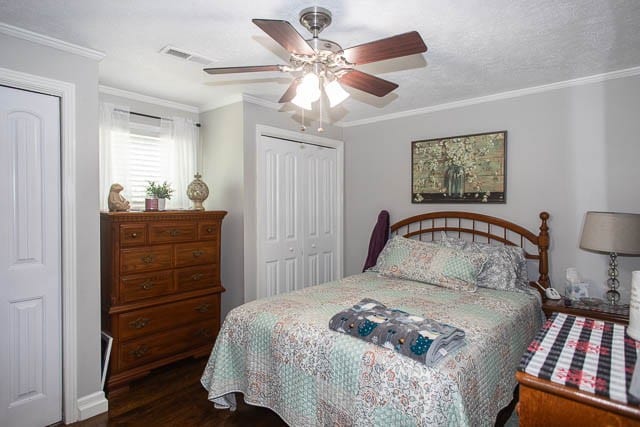 bedroom featuring dark wood-type flooring, ceiling fan, and ornamental molding