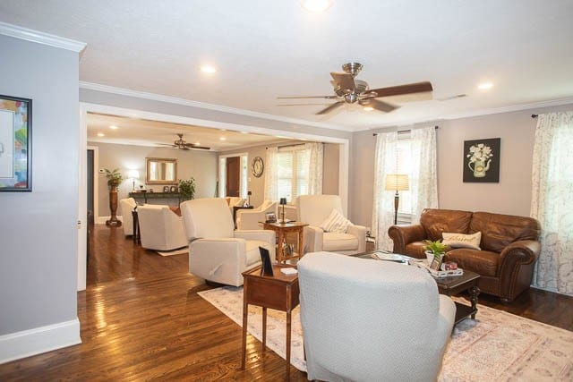 living room with dark hardwood / wood-style floors, ceiling fan, and crown molding