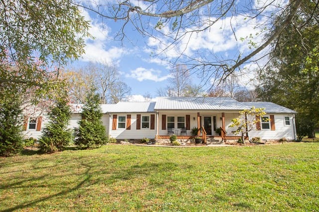 ranch-style home featuring a front lawn and covered porch