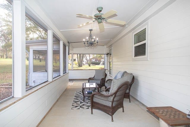 sunroom / solarium featuring ceiling fan with notable chandelier