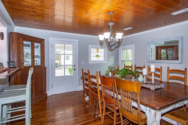 dining room with an inviting chandelier, dark wood-type flooring, and ornamental molding