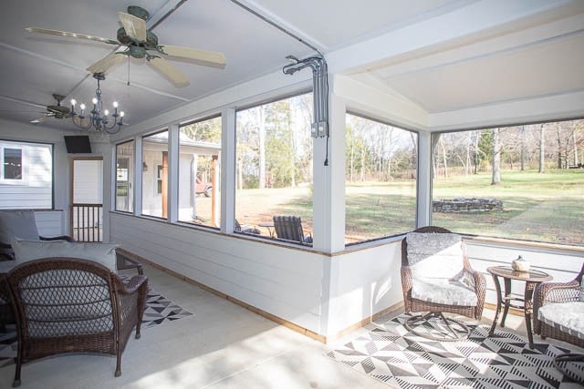 sunroom / solarium with plenty of natural light, ceiling fan with notable chandelier, and lofted ceiling